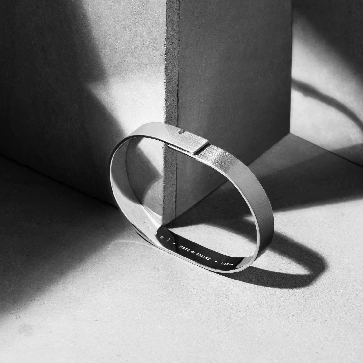 nature morte minimaliste fond brut béton d'un bracelet homme forme de jonc fermé Ursul Paris